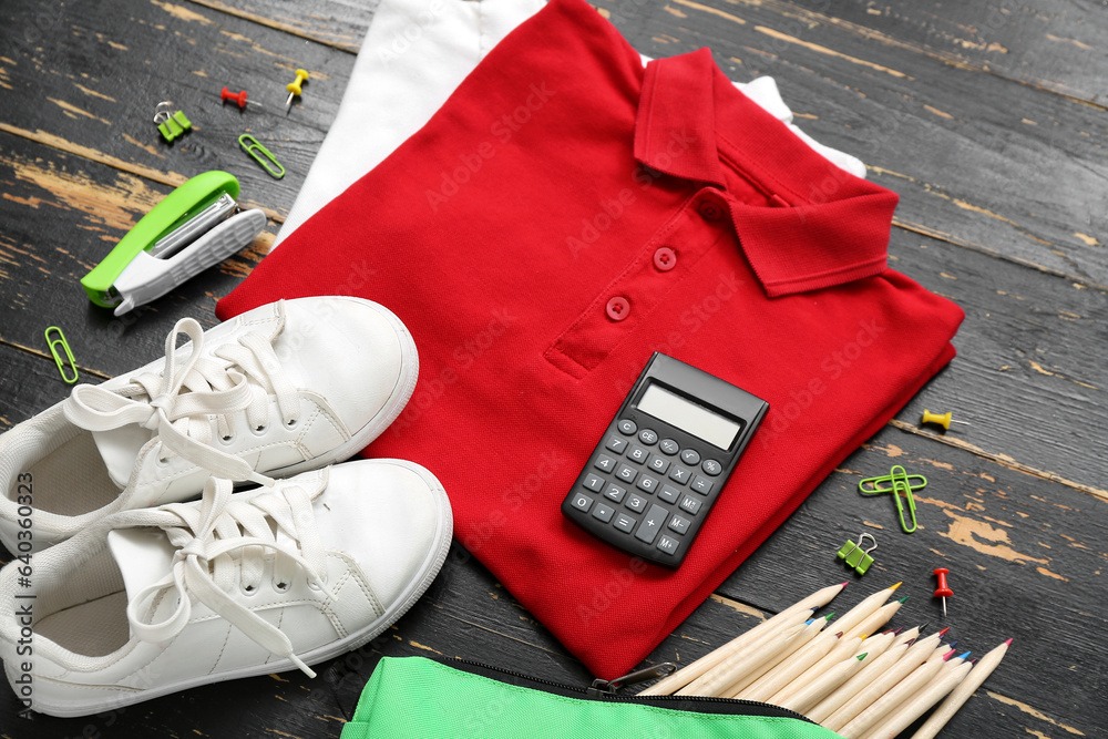 Different stationery with stylish school uniform on brown wooden background