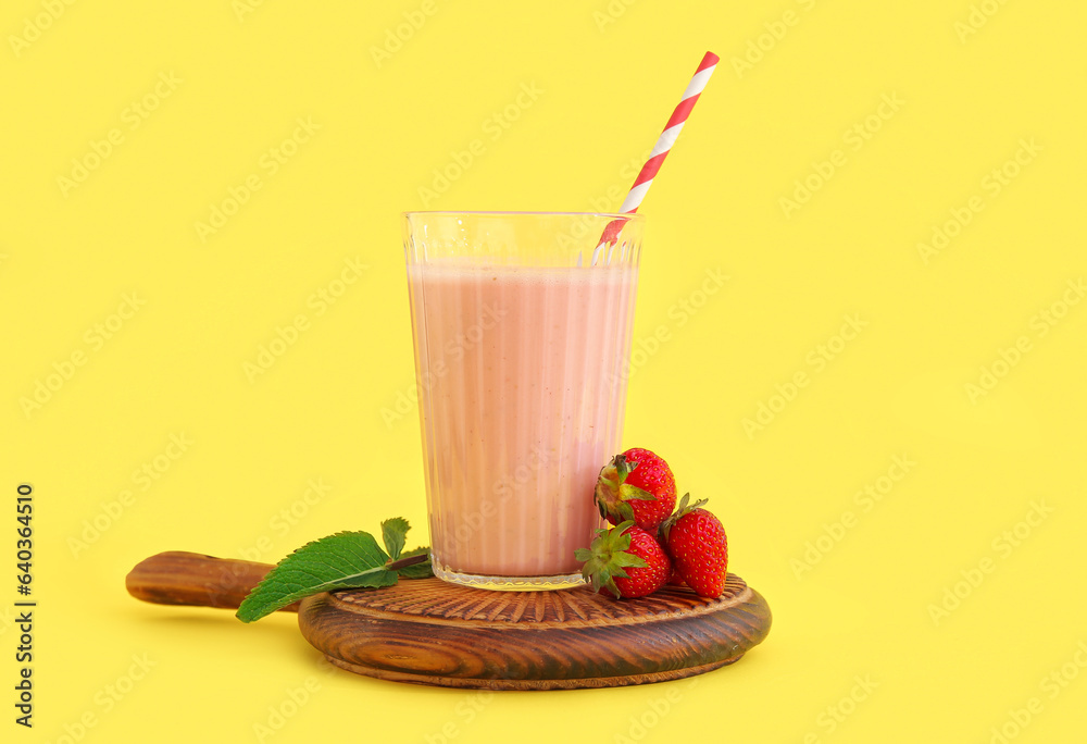 Glass of tasty strawberry smoothie on yellow background