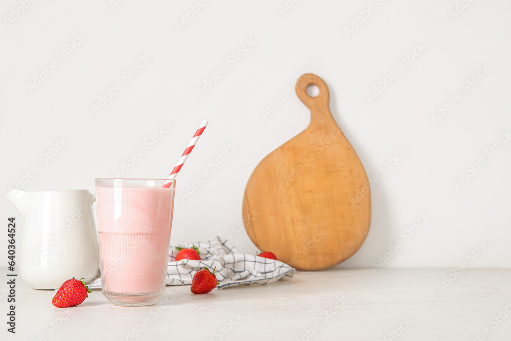 Glass of tasty strawberry smoothie on light background