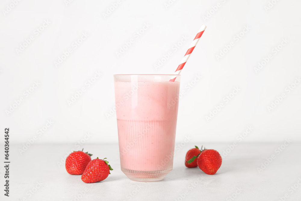 Glass of tasty strawberry smoothie on light background