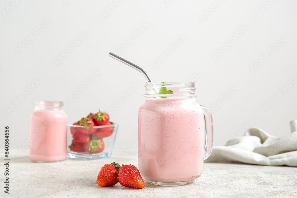 Mason jar of tasty strawberry smoothie on table