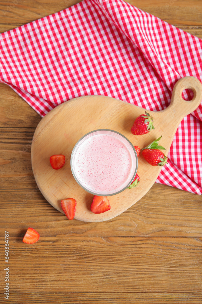 Glass of tasty strawberry smoothie on wooden background