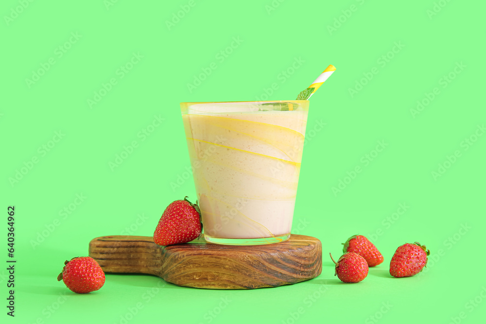 Glass of tasty strawberry smoothie on green background