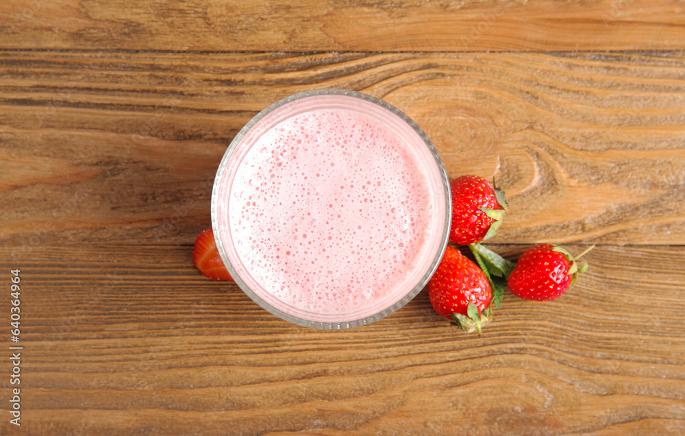 Glass of tasty strawberry smoothie on wooden background