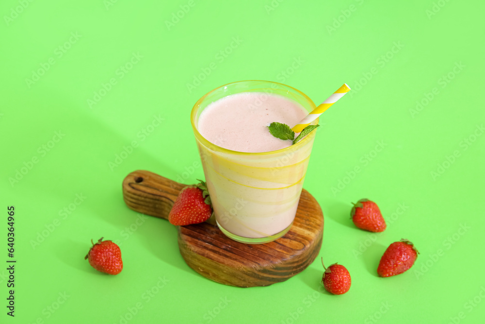 Glass of tasty strawberry smoothie on green background