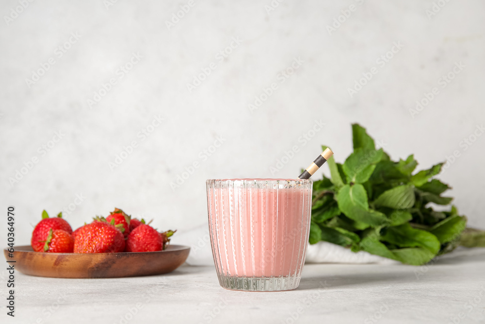 Glass of tasty strawberry smoothie on light background