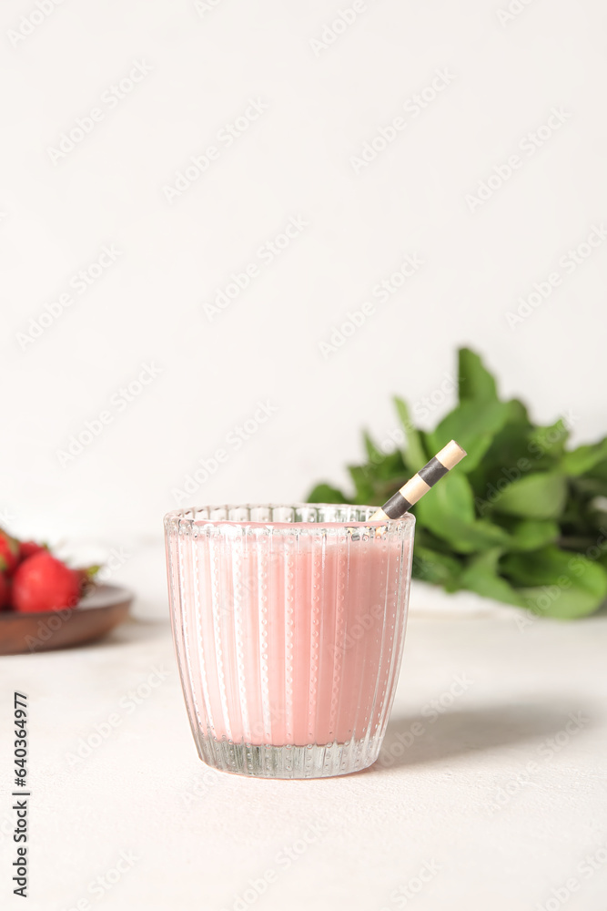 Glass of tasty strawberry smoothie on light background