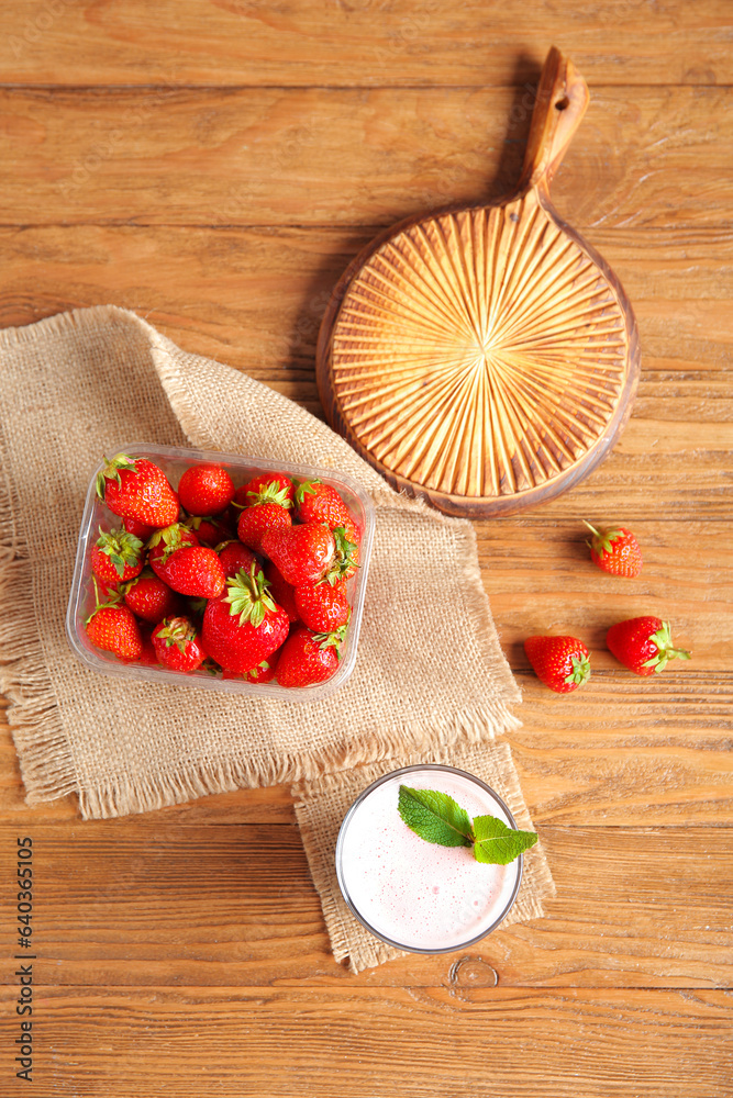 Glass of tasty strawberry smoothie on wooden background