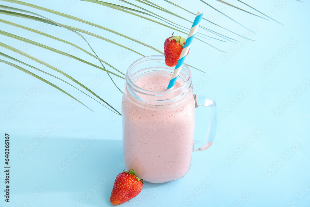 Mason jar of tasty strawberry smoothie on blue background