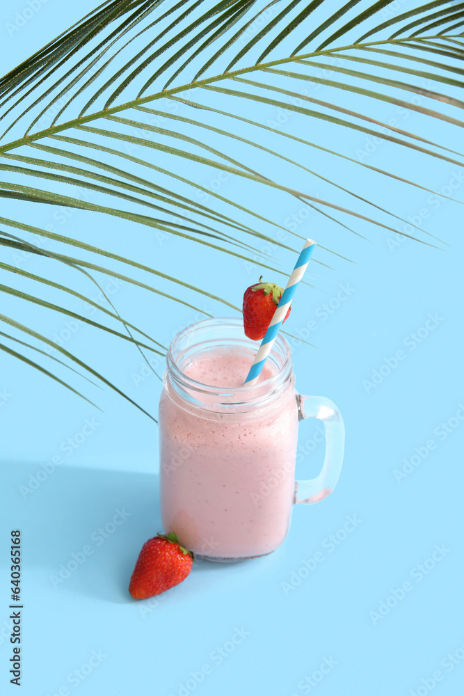 Mason jar of tasty strawberry smoothie on blue background