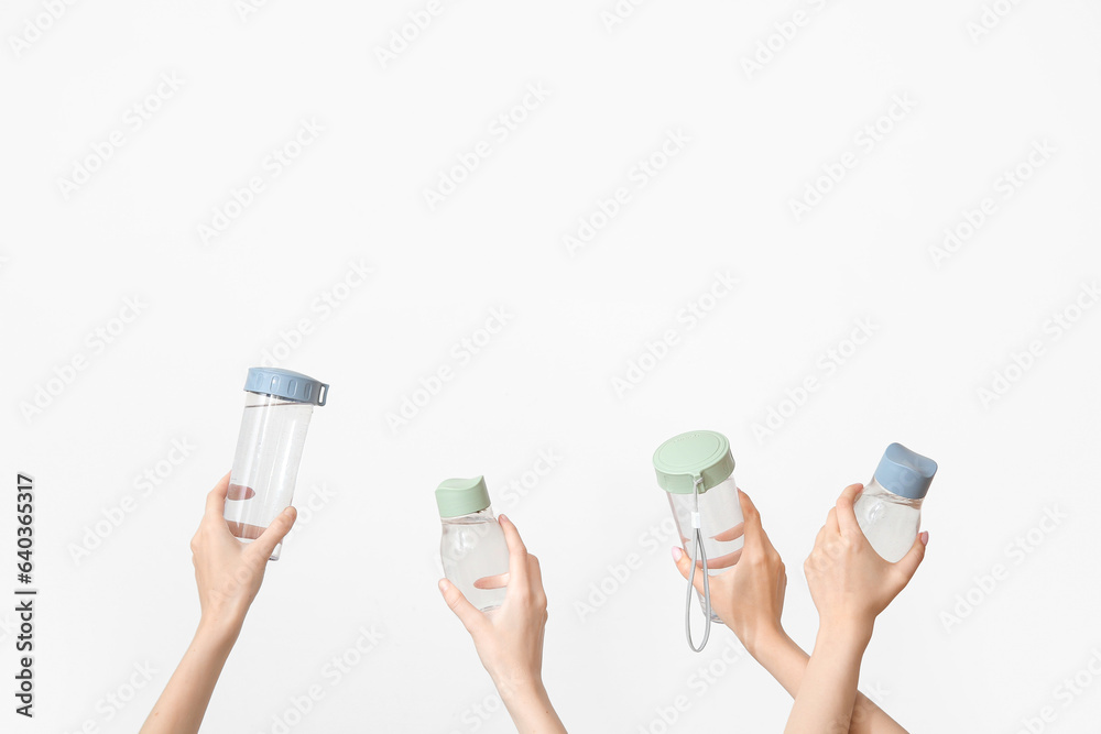 Female hands with bottles of fresh water on light background