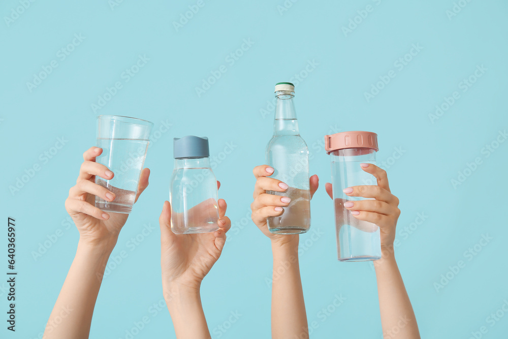 Female hands with bottles and glass of cold water on blue background