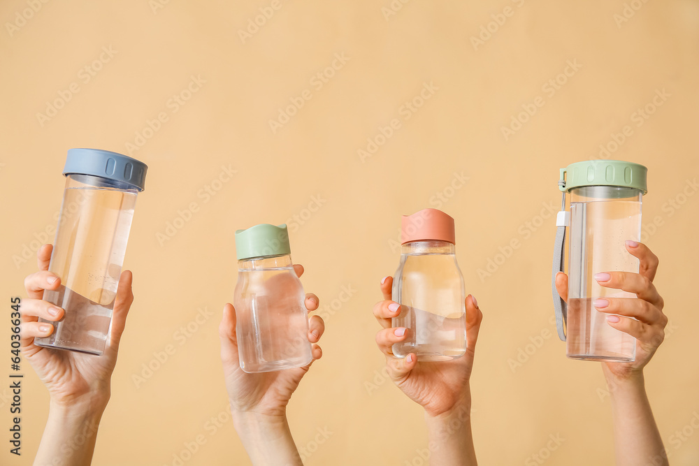 Female hands with bottles of cold water on beige background