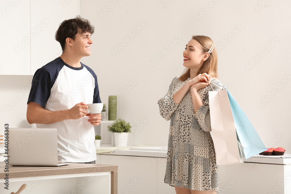 Young couple with shopping bags in kitchen