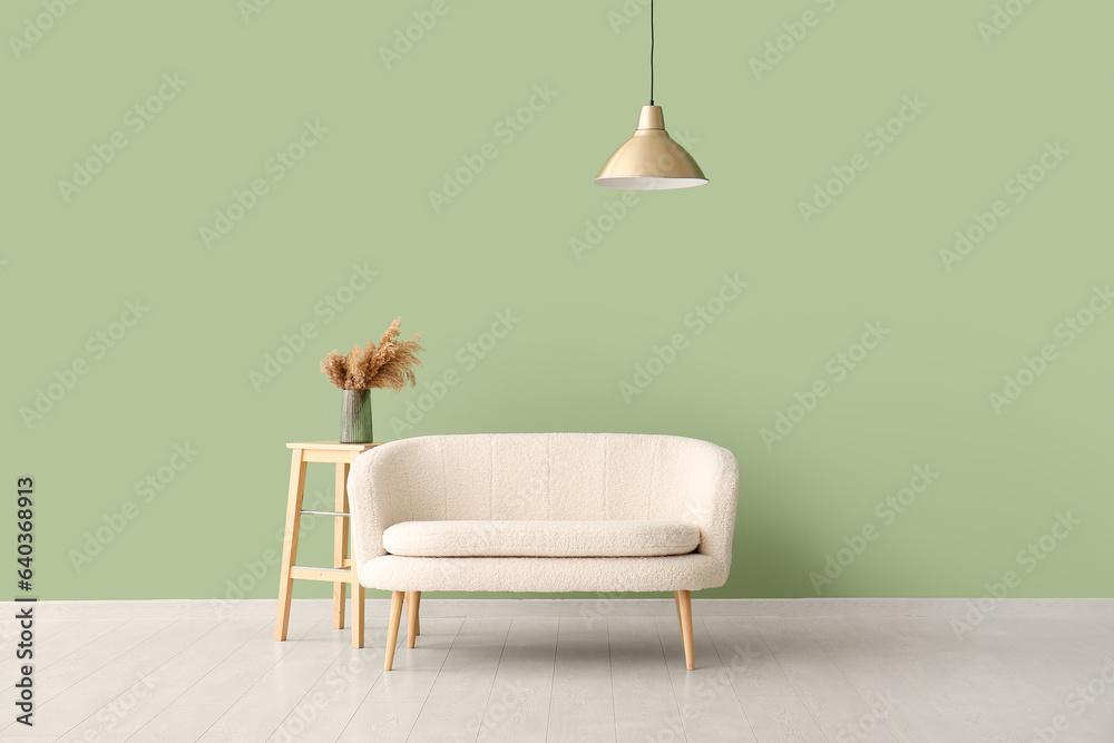 White sofa and vase with pampas grass on table near green wall