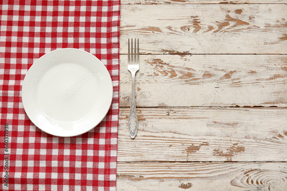 Clean plate, fork and napkin on light wooden background