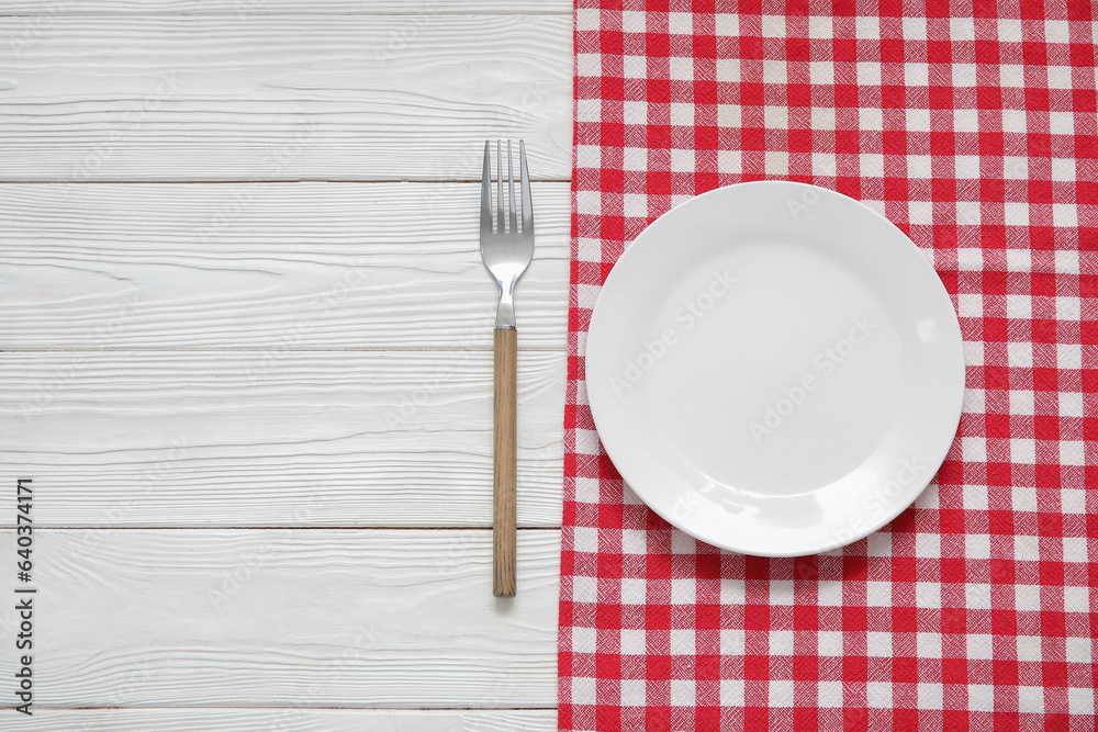 Clean plate, fork and napkin on white wooden background