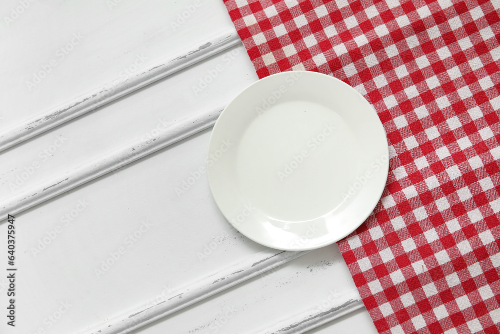 Clean plate and napkin on white wooden background