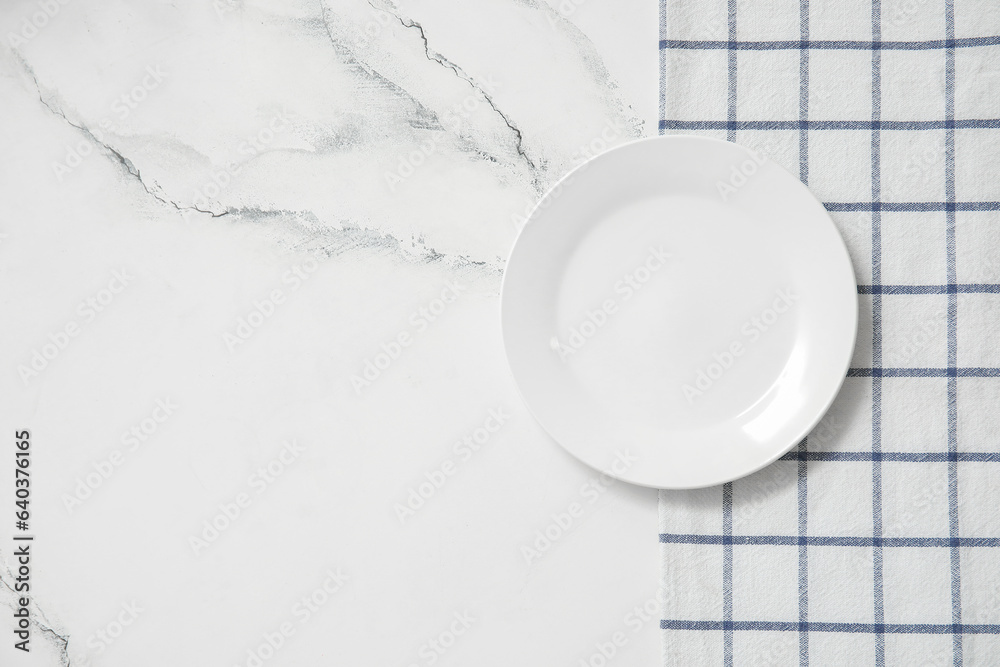 Clean plate and napkin on white marble background