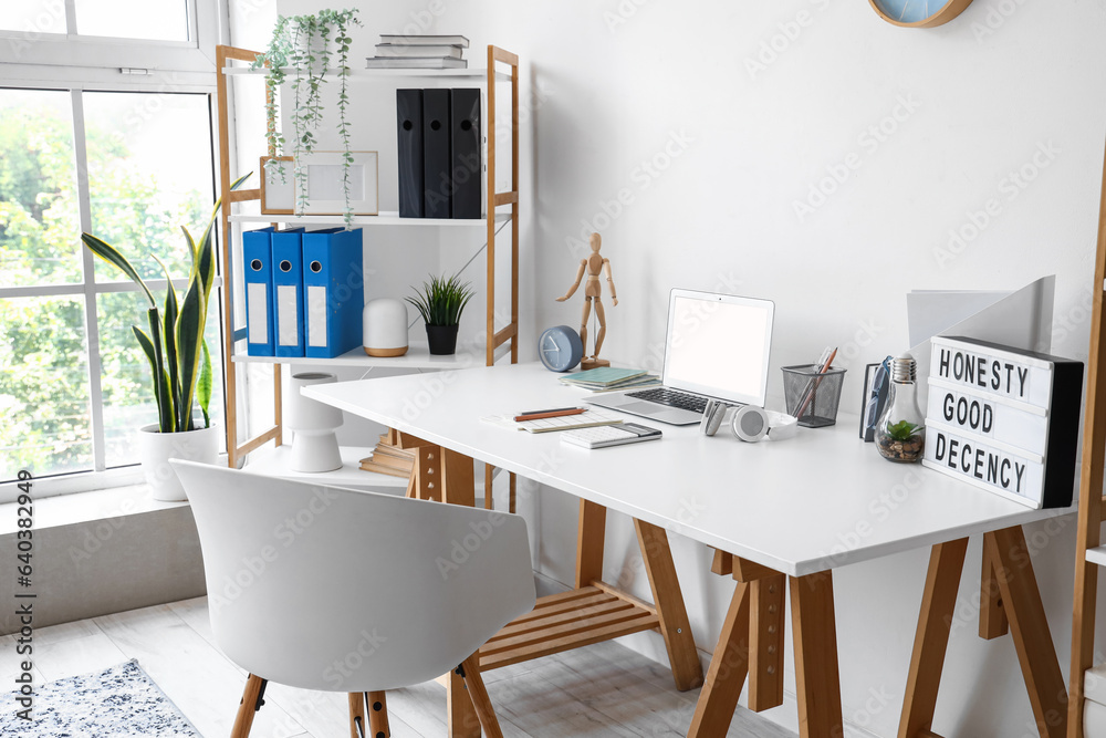 Modern workplace with laptop in interior of light office