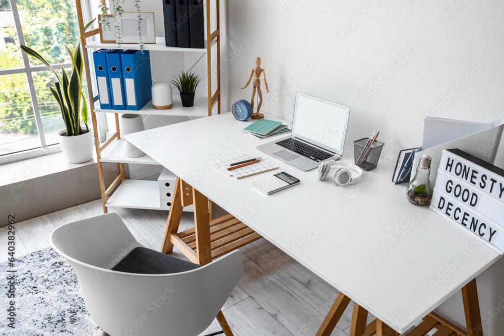 Modern workplace with laptop in interior of light office