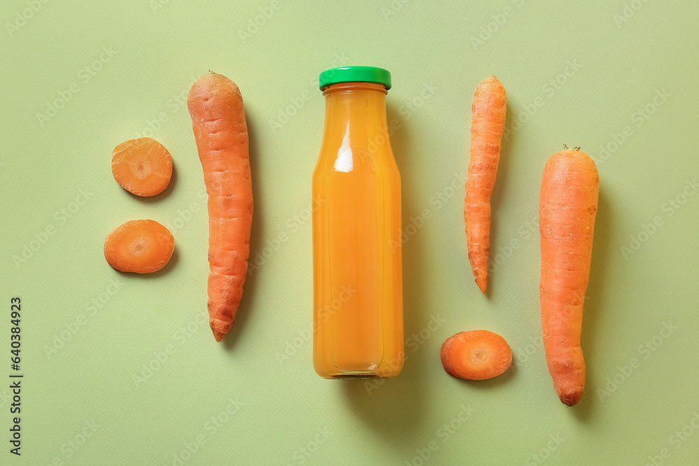 Bottle of fresh carrot juice on green background