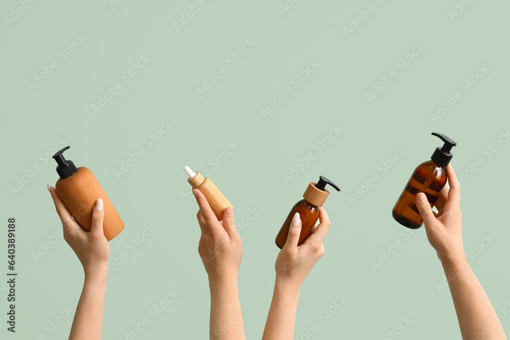 Women with bottles of cosmetic products on green background