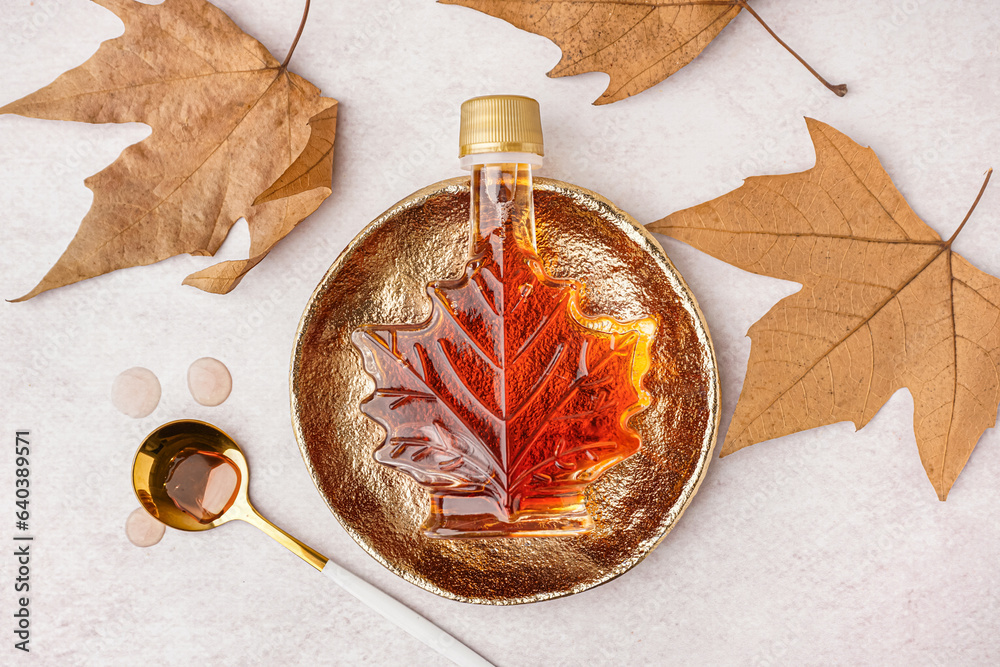 Bottle of tasty maple syrup on light background