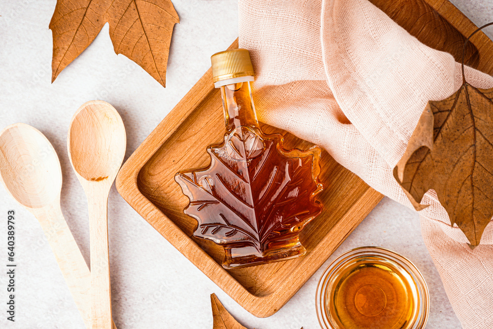 Bottle of tasty maple syrup on light background