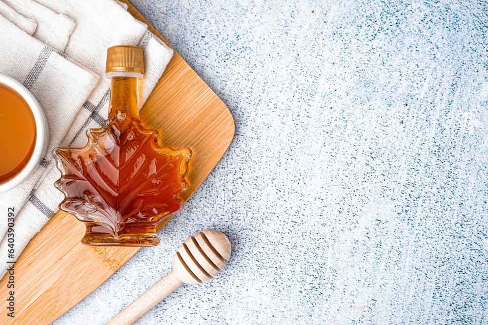 Bottle of tasty maple syrup on grey background