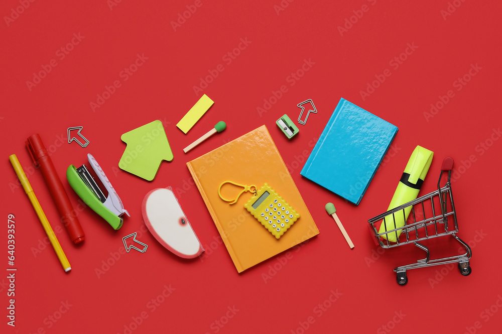 Shopping cart with different school stationery on red background