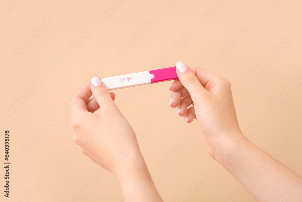 Female hands with positive pregnancy test on color background