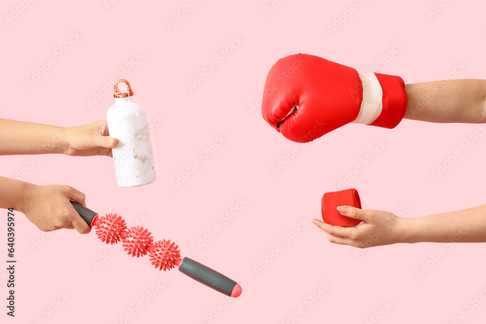 Female hands different sports equipment on pink background