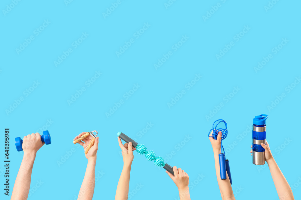 Female hands different sports equipment on blue background