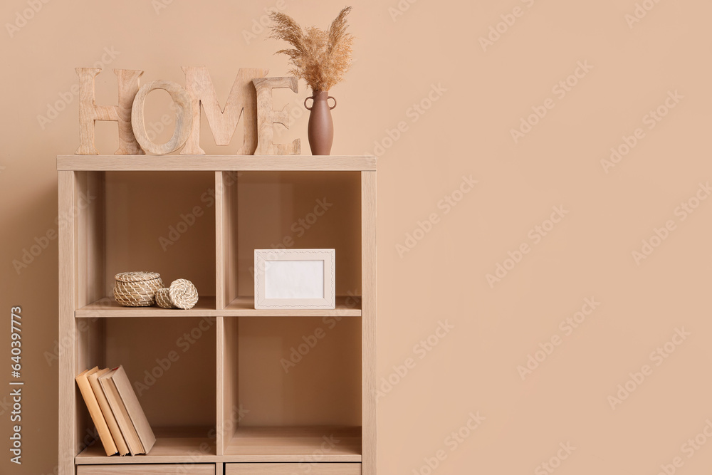 Wooden shelving unit with decor near beige wall