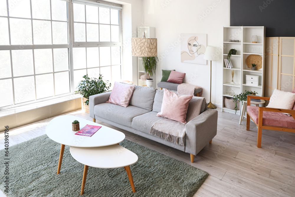 Interior of light living room with grey sofa and stylish coffee table