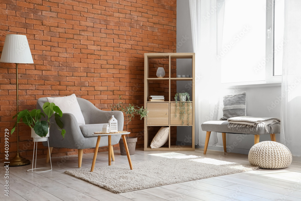 Stylish grey armchair and coffee table in interior of living room