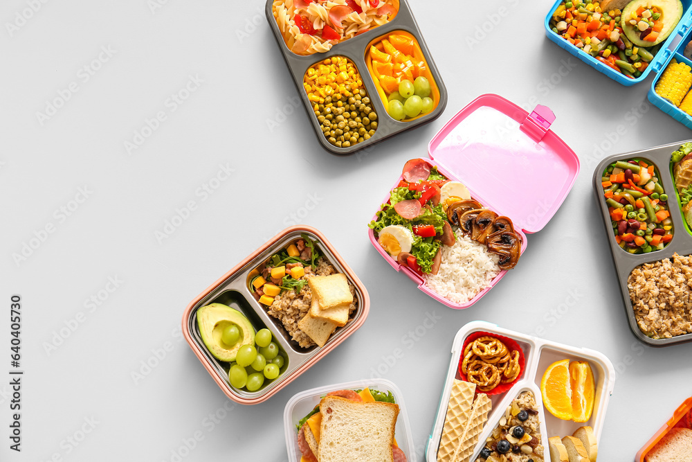 Many lunchboxes with different delicious food on grey background