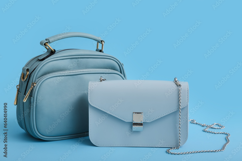 Stylish blue bags on color background