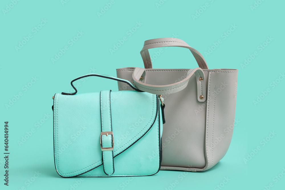 Different stylish handbags on turquoise background