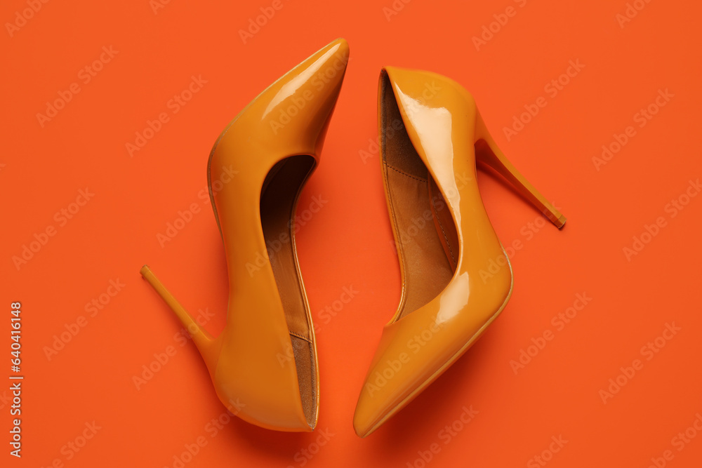 Stylish yellow high heels on orange background