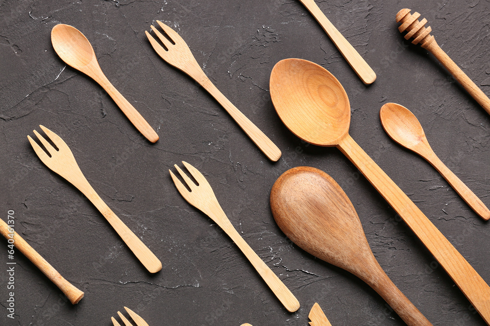 Wooden dipper, spoons and forks on black background