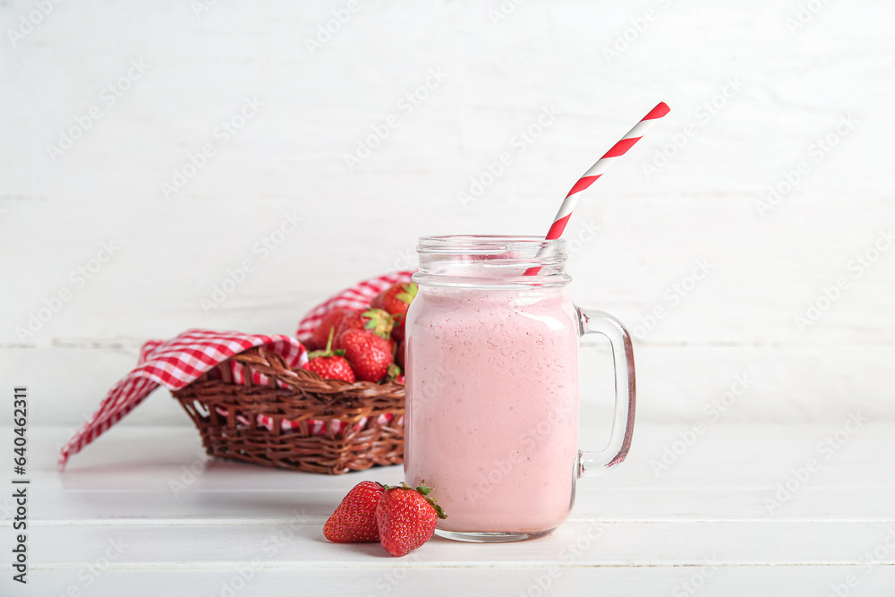 Mason jar of tasty strawberry smoothie on table