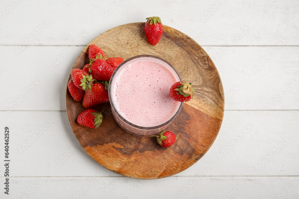 Glass of tasty strawberry smoothie on light wooden background