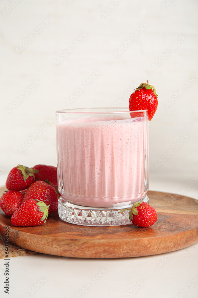 Glass of tasty strawberry smoothie on light background