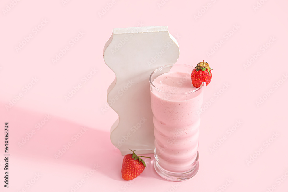 Glass of tasty strawberry smoothie on pink background