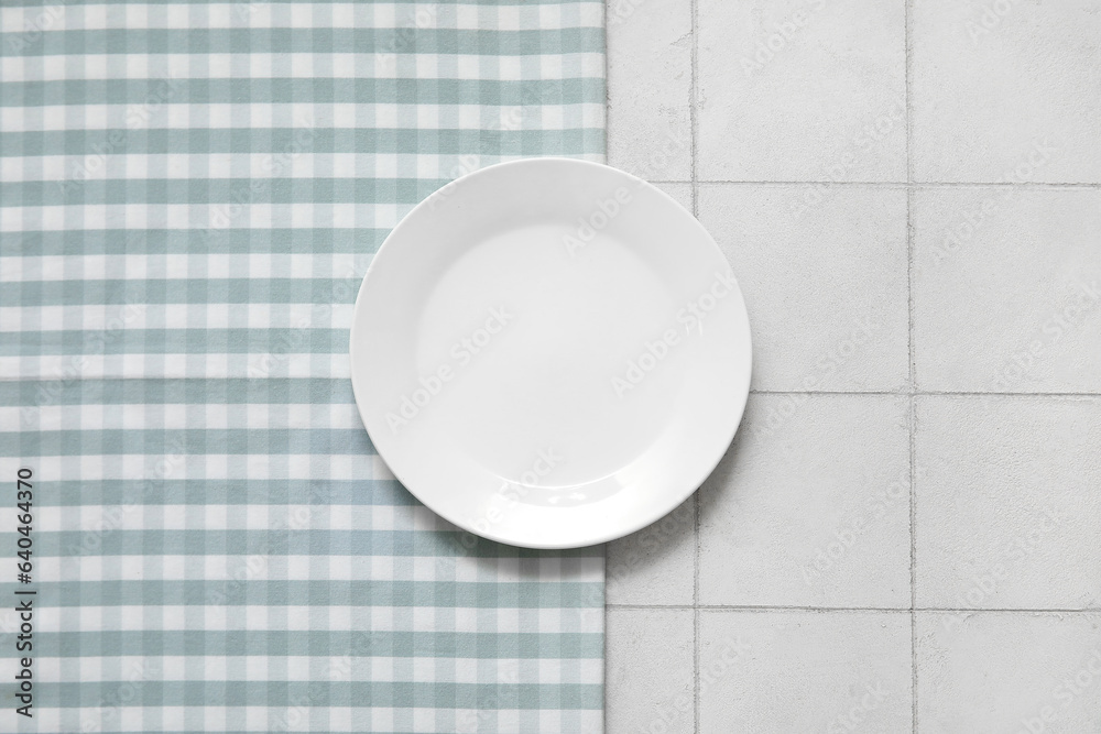 Clean plate and napkin on white tile background