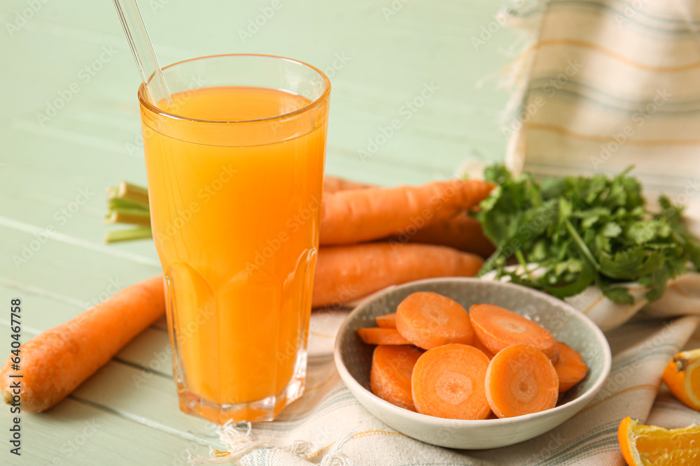 Glass of fresh carrot juice with parsley on green wooden table