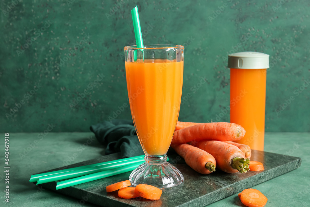 Glass and sports bottle of fresh carrot juice on green background