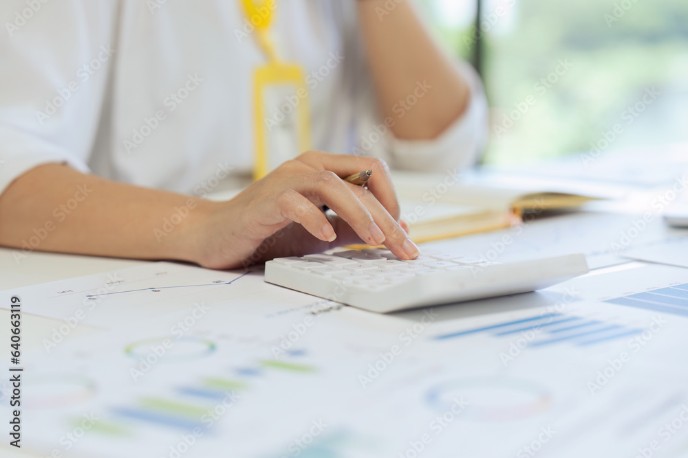 Businesswoman using a calculator to calculate numbers on a companys financial documents, she is ana